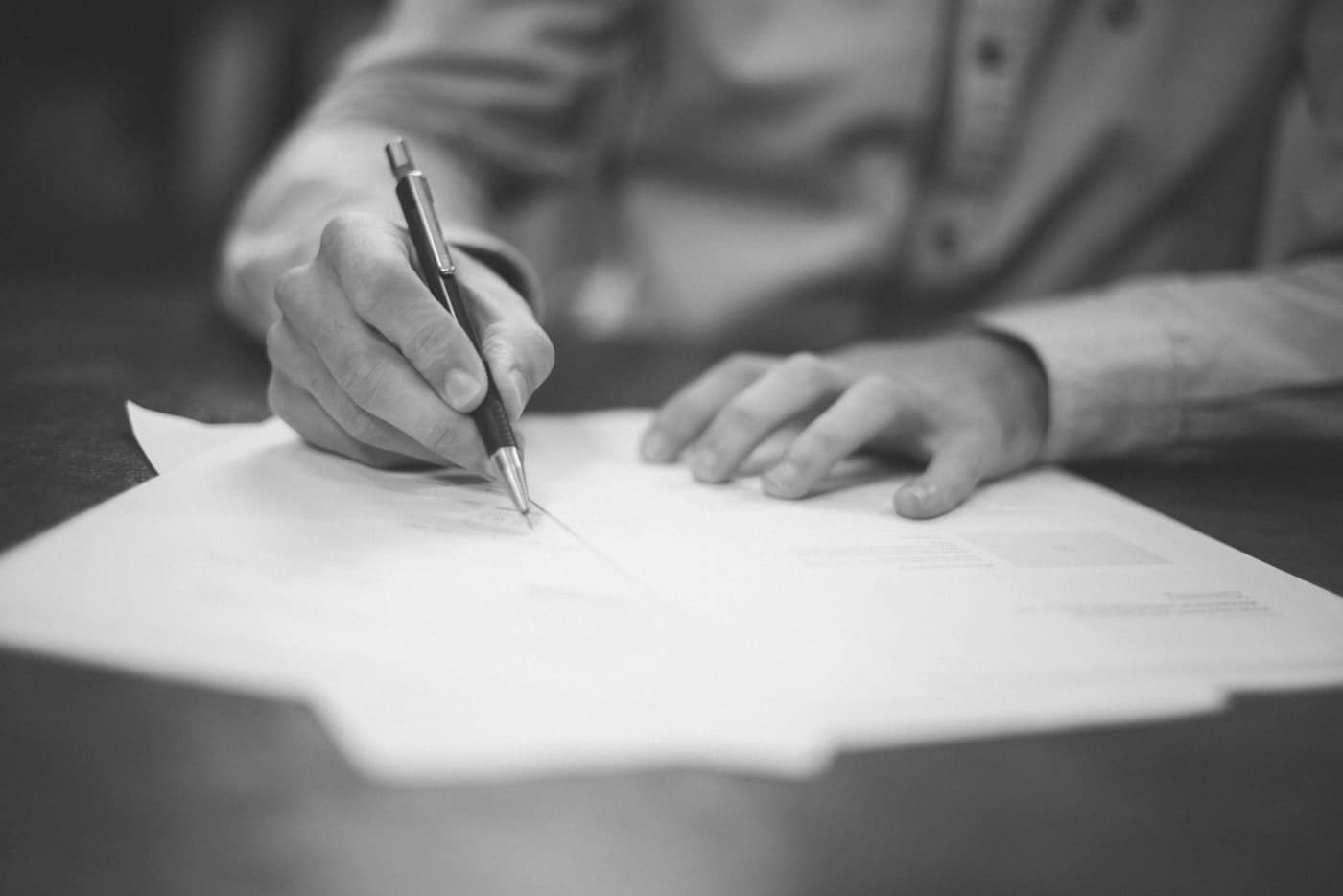 Main qui écrit sur un dossier posé à plat