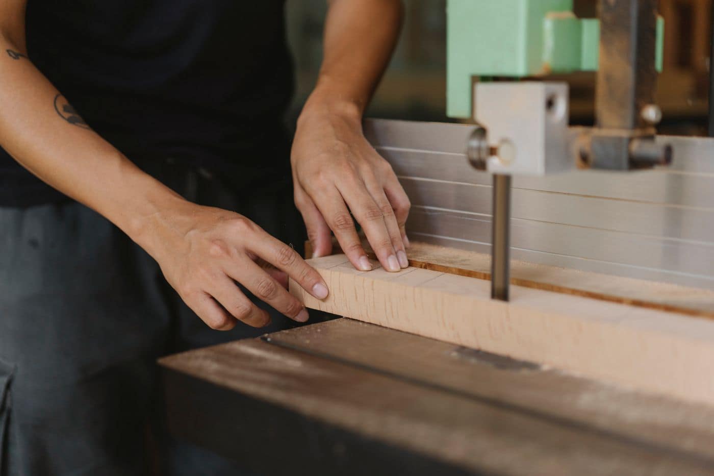 Les mains poussent une pièce de bois sur la scie